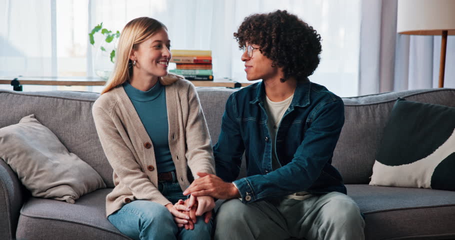 Happy, couple and holding hands for therapy, talking and laughing in office, smile and consultation. Appointment, man and woman with trust on sofa, relationship or services for pre marital counseling