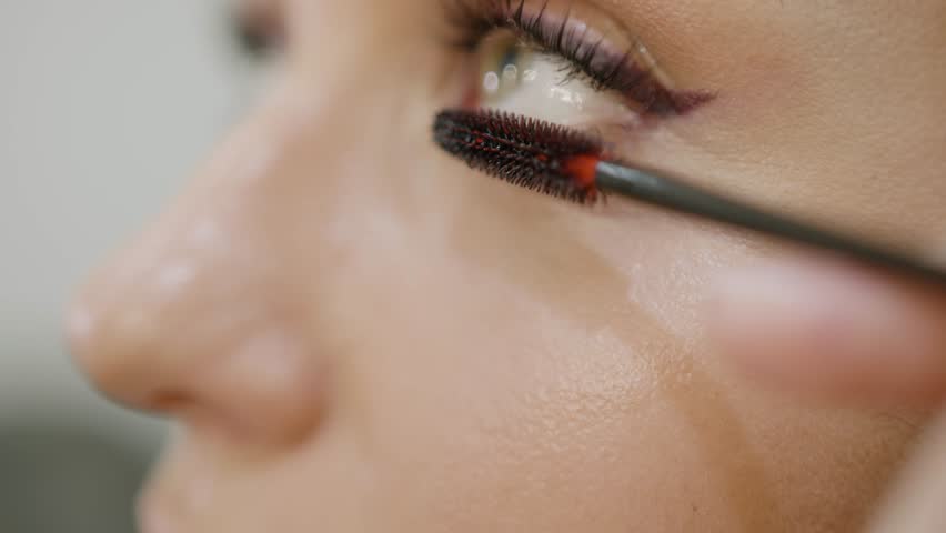 Eyelash tinting. Makeup artist applies mascara to model lower lashes. Close-up