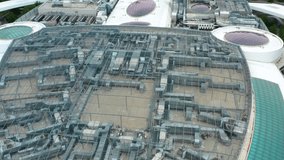 Angled orbit aerial view of shopping mall rooftop infrastructure with metal ventilation and HVAC elements surrounded by curved and oval glass skylights, representing industrial technology in urban bui - Powered by Shutterstock - Get 15% off with code: PIKWIZARD15