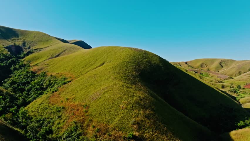 Aerial footage showcasing the rolling green hills and dramatic terrain of Madagascar under a clear blue sky, perfect for nature lovers and travel enthusiasts.