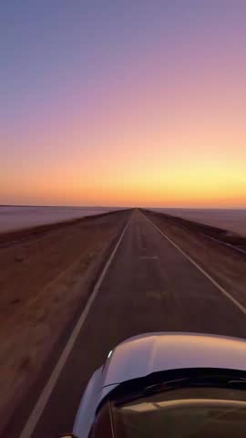 Driving forward on the road to heaven in Kutch, Gujarat, India the glowing white Rann shimmers endlessly on both sides while the sunset paints the sky in vibrant hues of orange and pink 4K