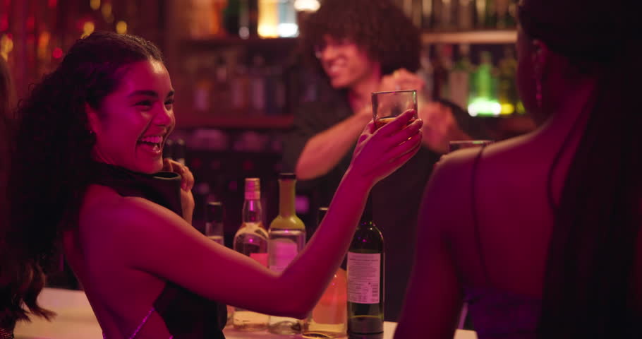 Cheers, drinking and woman friends at bar together for celebration, clubbing or social gathering. Party, smile and toast with happy people in pub or tavern at night for event, milestone or reunion