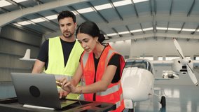 Aircraft maintenance crew working on laptop in hangar - slow motion - Powered by Shutterstock - Get 15% off with code: PIKWIZARD15