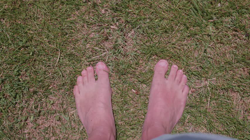 male bare feet from top angle walking on grass