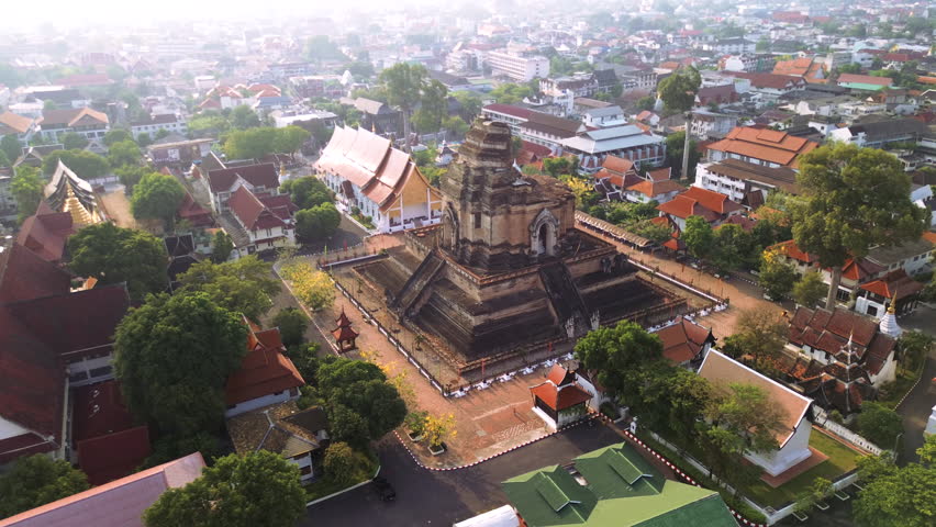 Aerial establishing of Chiang Mai Wat Chedi Luang temple surrounded by city buildings, aerial orbit