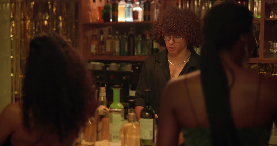 Bartender, women and mixing drinks at a club for customer, cocktail or happy hour at counter. Man, mixologist and people with alcohol beverage at bar or pub for cheers, social event and party