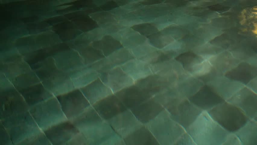 Abstract view of the lower floor of the swimming pool with bright green color at night and a few pool lights.