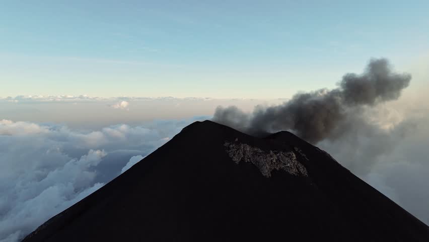 Black smoke rises from Fuego volcano in Guatemala, aerial orbit view