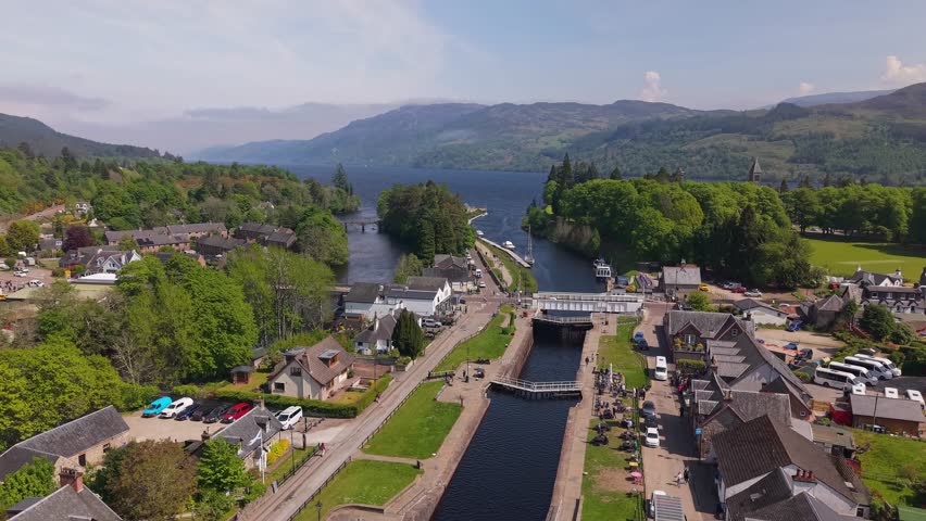 Aerial orbit of the stone bridge at Fort Augustus, Scotland, with the iconic Loch Ness and lush Highland landscape in the background