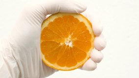 Gloved hand squeezing a juicy orange slice with fresh juice dripping down. The high-key background emphasizes the citrus texture, freshness, and motion of fruit pressing - Powered by Shutterstock - Get 15% off with code: PIKWIZARD15