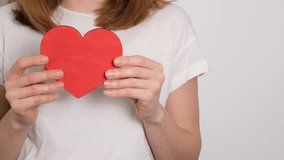 A young woman in a white t-shirt is holding a heart painted with rainbow colors. A strong visual concept symbolizing LGBTQ pride, love, inclusion, and identity. - Powered by Shutterstock - Get 15% off with code: PIKWIZARD15