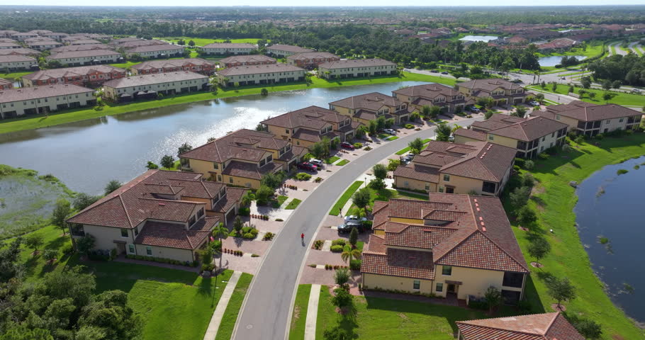 Condo homes in Florida closed living community with lake water in the middle. Family houses as example of real estate development in American suburbs
