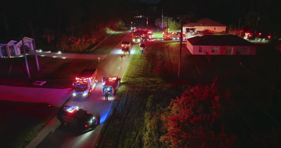 First responders investigating fire hazard of private house at night. Emergency service personnel responding to carbon monoxide accident on Florida residential street.