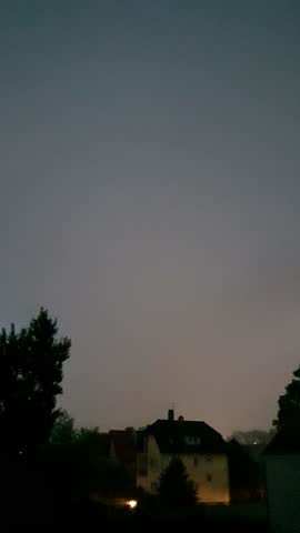 thunderstorm in the city, heavy rain with lightning, large drops on tree leaves and asphalt