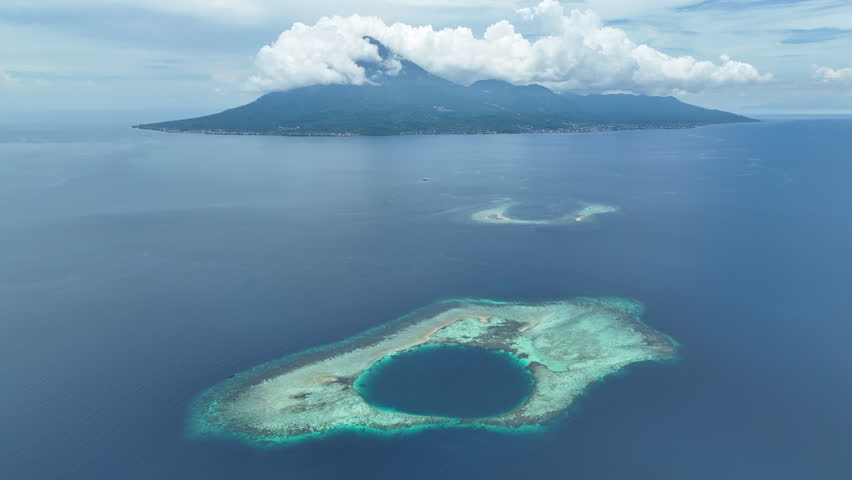 Seen from an aerial view, a picturesque atoll is found in the Molucca Sea near the island of Halmahera, Indonesia. Atolls form as the volcanic islands they surround slowly sink over geologic time.