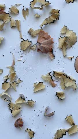 Close-up of sharpened yellow pencil with wood shavings on white background, drawing heart shape. Creative education or art concept captured in macro shot