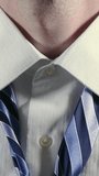 Close-up vertical shot of a man adjusting and tying a necktie, wearing a crisp white dress shirt. A detailed, professional scene ideal for business, fashion, or morning routine concepts.	 - Powered by Shutterstock - Get 15% off with code: PIKWIZARD15