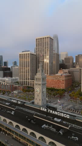 An aerial photograph captures the breathtaking skyline of San Francisco during dawn, showcasing the vibrant Port and its iconic buildings, while gentle misty fog gracefully rolls over the bay area
