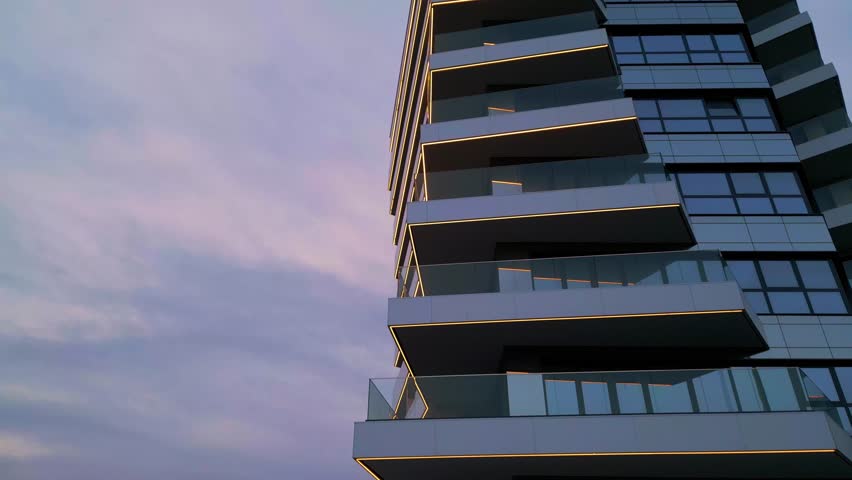 Modern residential building with glass balconies and LED lighting at sunset. Urban architecture and city living concept with soft sky reflections and evening ambiance