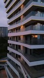 Modern residential building with glass balconies and LED lighting at sunset. Urban architecture and city living concept with soft sky reflections and evening ambiance - Powered by Shutterstock - Get 15% off with code: PIKWIZARD15