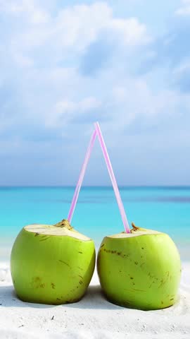 Fresh green coconuts fruit on sandy Maldives beach with turquoise sea background. travel destination. Vertical footage