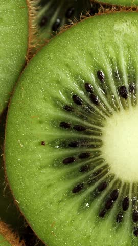 A lot of sliced Kiwi rotating. Ripe Tropical fruits closeup. Vertical footage
