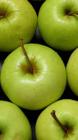 many green apples rotating. Fruits background. Vertical footage