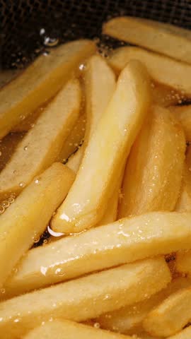 Cooking french fries potatoes in deep fryer. Closeup. Vertical footage
