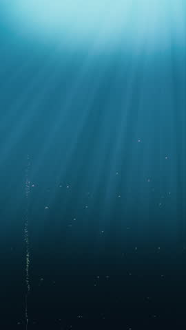 Elegant rays of sunlight shining from above penetrate deep clear blue water.  Small bubbles rising up. Seamless looping 4K animation.