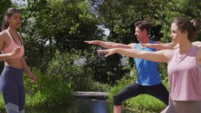 fitness instructor greeting group pondside guiding students into warrior II pose ensuring form. Wellness, outdoor, serenity, balance, exercise, nature, harmony - Powered by Shutterstock - Get 15% off with code: PIKWIZARD15
