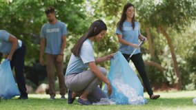 Volunteer team picking litter in sunlit park, initiating floating emoji icons showing green cleanup. Community, environment, eco-friendly, conservation, teamwork, outdoor, vibrant - Powered by Shutterstock - Get 15% off with code: PIKWIZARD15