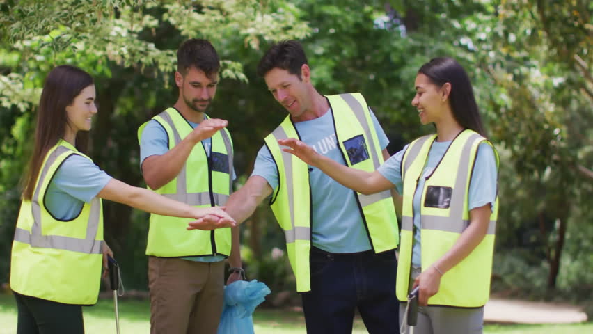 Community volunteers stacking hands activating hearts and likes rising above celebrating teamwork. Team, collaboration, unity, friendship, positivity, environmental, outdoor