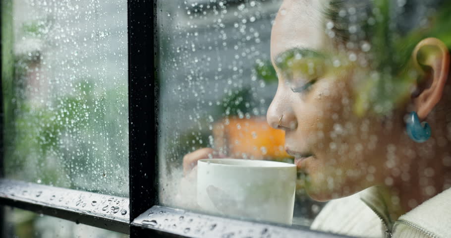 Woman, thinking and drinking coffee with window rain drops for winter season, cold weather or dream at home. Female person, relax and wonder with thought or mug for caffeine or condensation at house