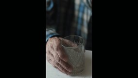 hands of an old man holding a glass of water close-up, an elderly man holds a glass of water in his hands, vertical video - Powered by Shutterstock - Get 15% off with code: PIKWIZARD15