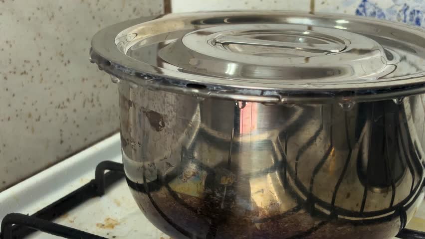 Close the stainless steel pot on the stove, which had water in it that was so hot that the lid was pushed open and hot steam was spurting out.