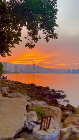 A person casting a fishing line against a vibrant sunset over the ocean. Silhouette of fishing man on coast of sunset sea. Fisherman at Sunset. A silhouette of a man fishing on a dock at sunset. 