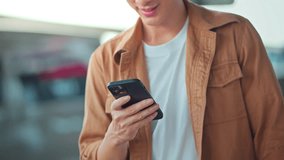 Close-up of asian man’s hands using smartphone while standing near shopping mall in city street – online communication, messaging, social media, and urban lifestyle with digital connection on the go - Powered by Shutterstock - Get 15% off with code: PIKWIZARD15