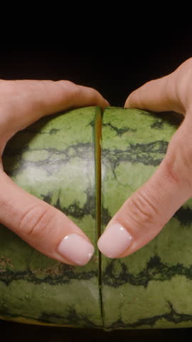 Close-Up of Woman Splitting Green Watermelon into Two Halves with Both Hands as Camera Slides Through the Center Gap Using Dolly Slider Movement.