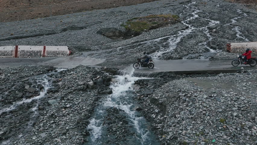 Enduro Bikers Cross Cold Water Stream in High Altitude Valley Drone View