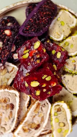 Sliced ​​Turkish delight assortment with cream filling, pistachio, almond, hazelnut, figs and cranberry rotating on the plate. Local name: fistikli fitil lokum