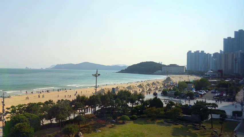 Panoramic view of Haeundae Beach with golden sand, city skyline, and visitors enjoying the seaside in Busan
