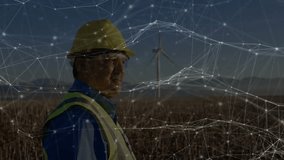 Network overlay drifting over engineer in helmet, vest, causing head turning toward wind turbine. Technology, innovation, sustainability, infrastructure, connectivity, future, environment - Powered by Shutterstock - Get 15% off with code: PIKWIZARD15
