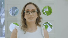 Medium shot clip of a young woman with natural makeup and glasses, smiling at the camera. - Powered by Shutterstock - Get 15% off with code: PIKWIZARD15