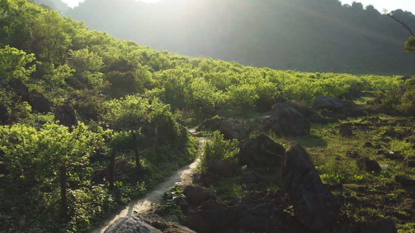 Drone tracks a dirt path winding through trees, rocks, and valleys in Mộc Châu’s Na Ka region