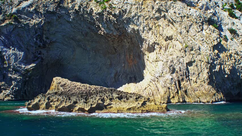 Panoramic scenic view of the rocky coastline of Mallorca with steep cliffs, deep blue sea on a clear summer day. Tracking shot