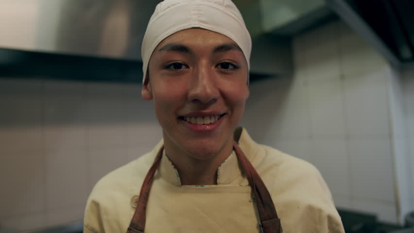 Latino chef prepares food in kitchen in Colombia He smiles at the camera Happy about his work