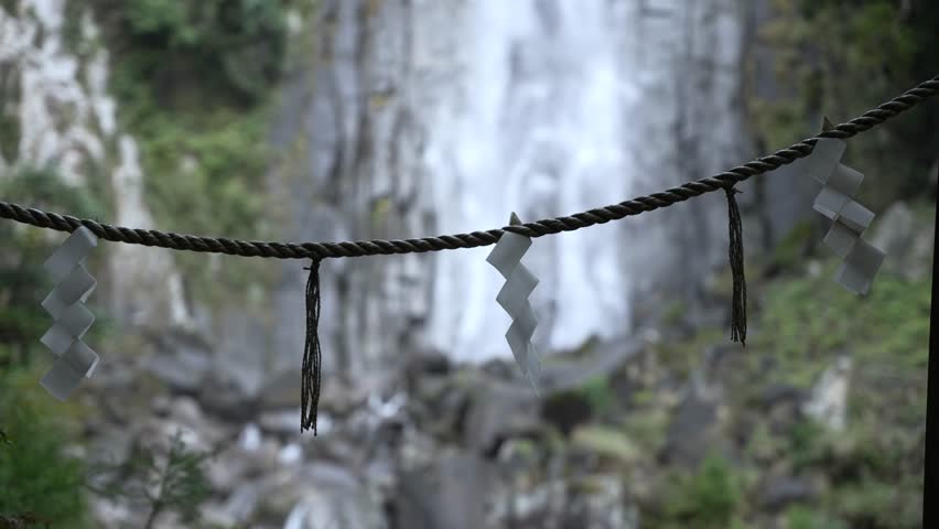 Close up of shide papers hanging on rope in front of Nachi Falls in Nachikatsuura, Japan