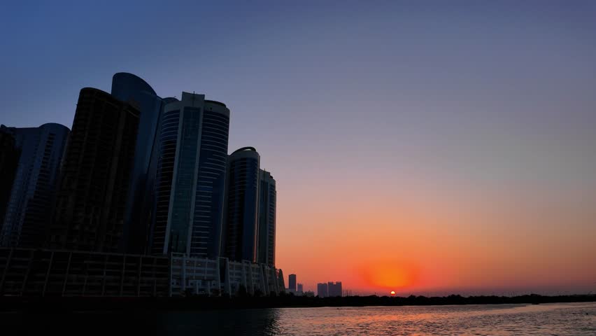 Sunset with the sun just on the horizon as seen from Al Reem Island looking towards Abu Dhabi, United Arab Emirates