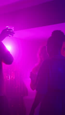 Friends toasting drinks at a nightclub party in slow motion