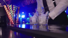 Bartender pouring alcoholic beverage into glasses with ice in slow motion - Powered by Shutterstock - Get 15% off with code: PIKWIZARD15